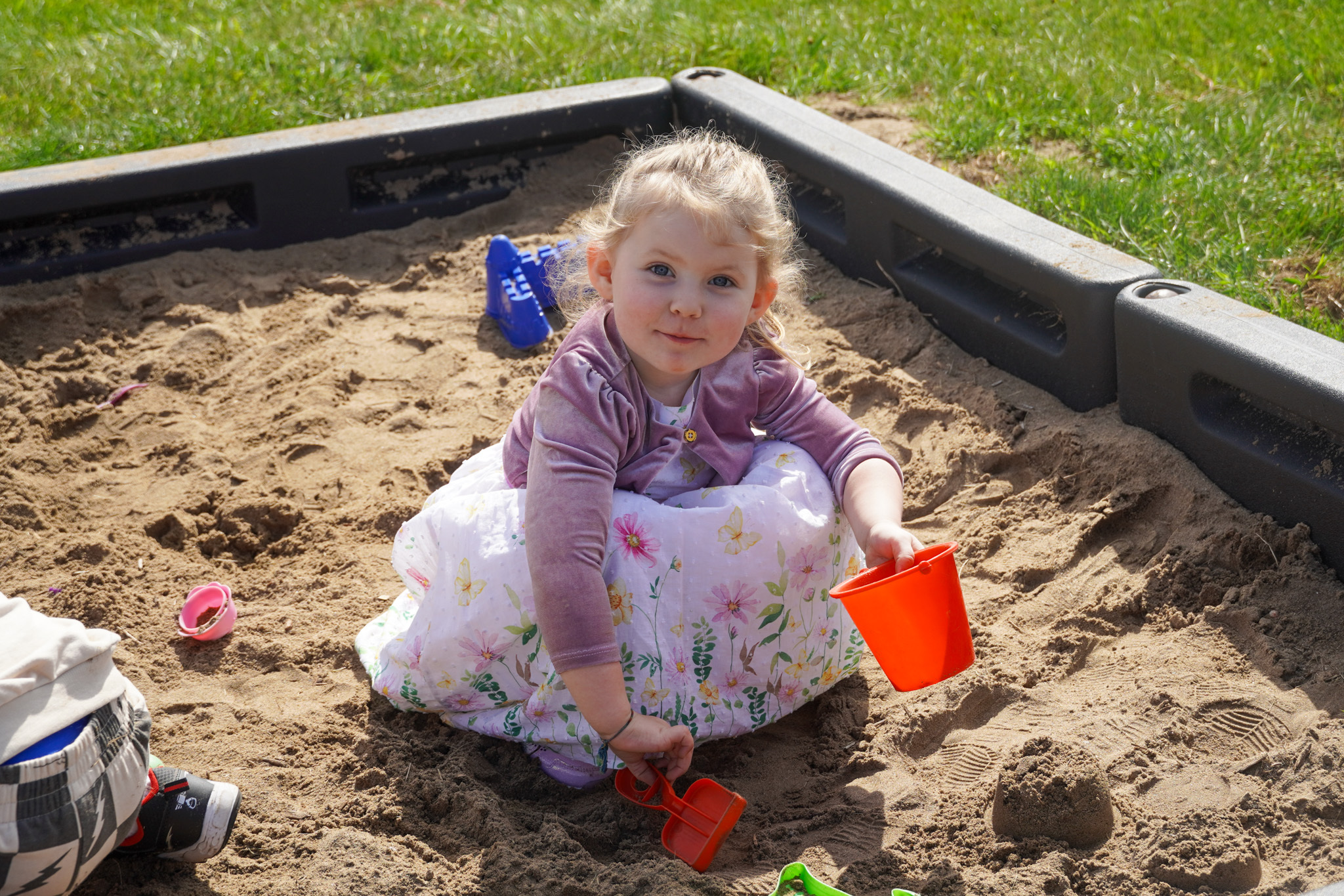 little girl playing in the sand box at recess smiling at the camera